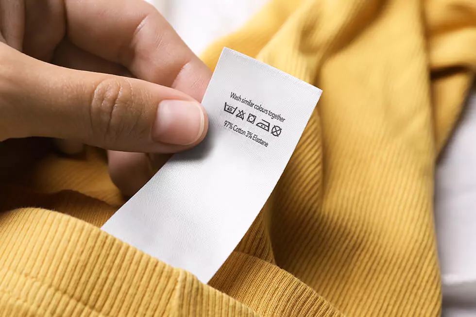 Nahaufnahme eines Care Labels in gelbem Pullover